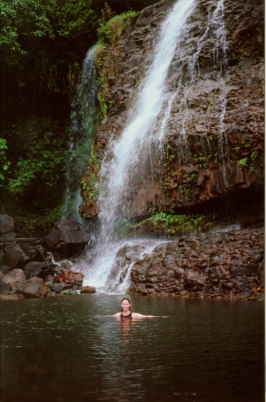 Stasha swimming under a waterfall in Kauai